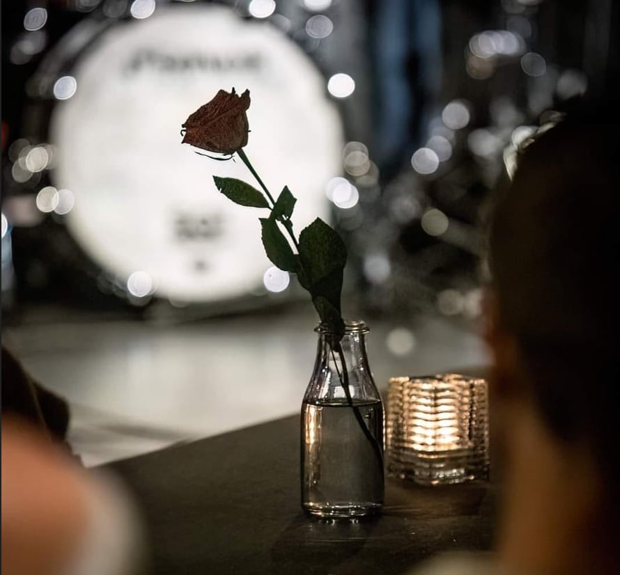 En ros i en flaska med vatten. i bakgrunden, ett trumset. bokeh